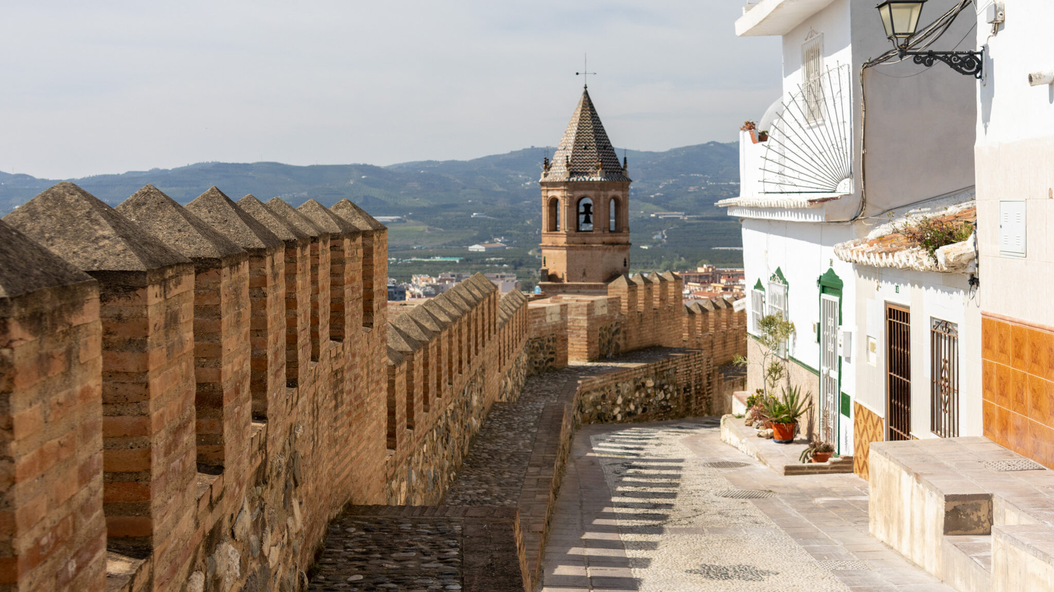 Murallas de la Medina Velez Malaga | Krista the Explorer Medieval city walls leading down hill in villgae.