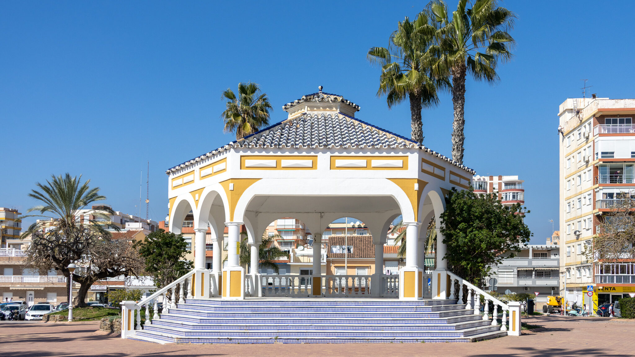 Painted bandstand with palm trees around it.