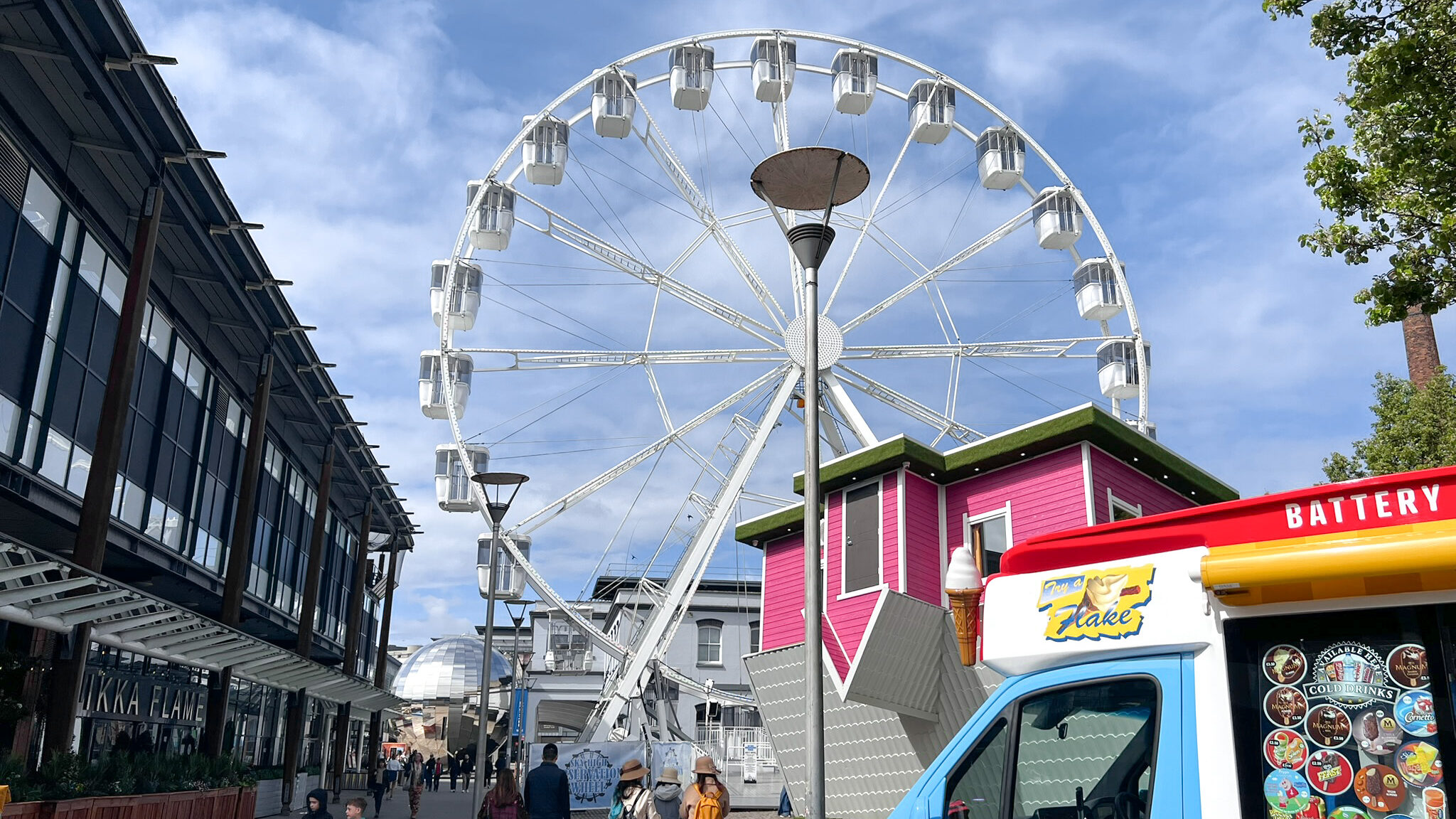 Large Ferris wheel in front of upside down house.