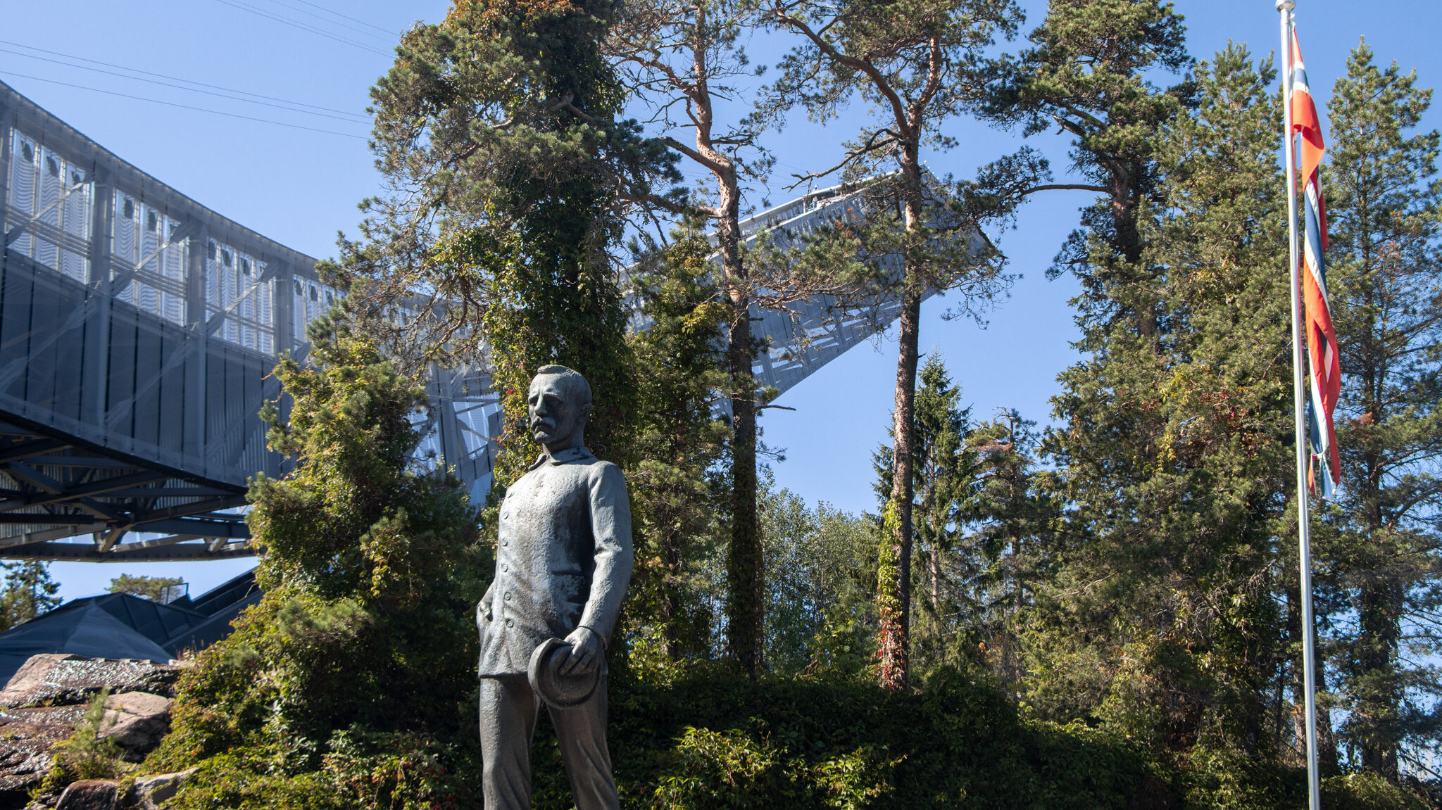 Historic ski jump with statue in front.