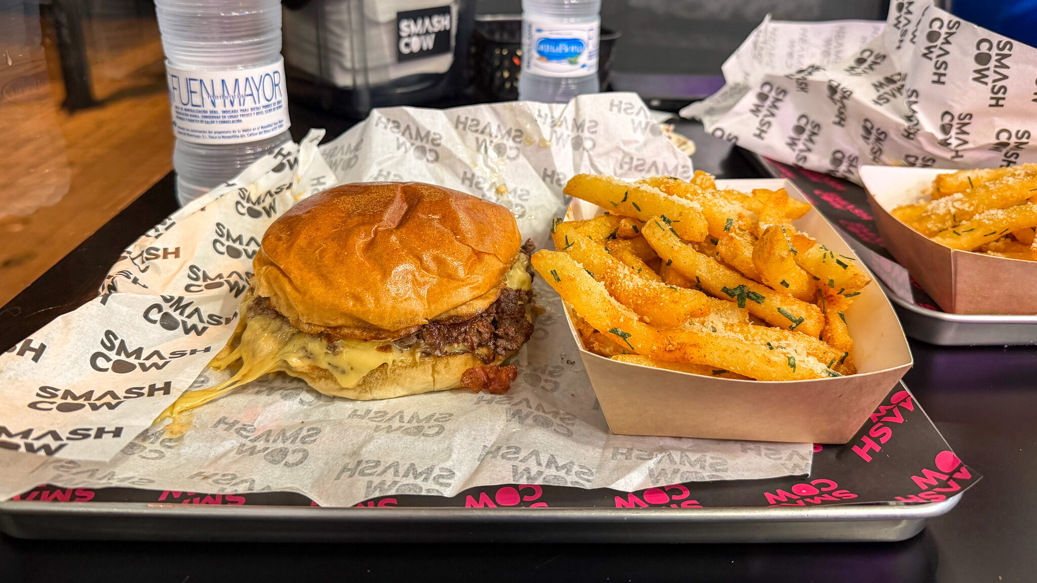 Smash Cow Zaragoza | Krista the Explorer Smash burger and seasoned fries served on tray.