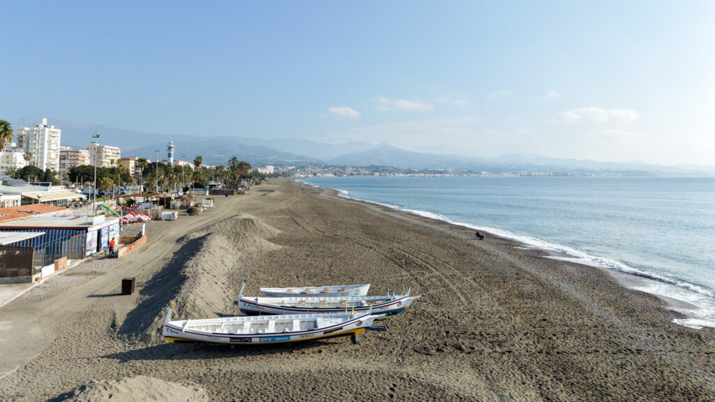 Beach at sunrise with boats on sand.