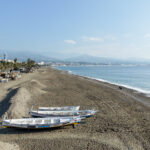Beach at sunrise with boats on sand.