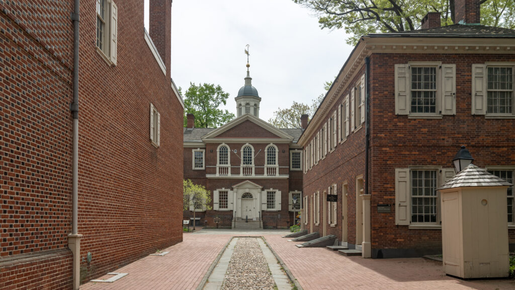 Brick courtyard with a central building that has white-trimmed arches and a domed cupola.