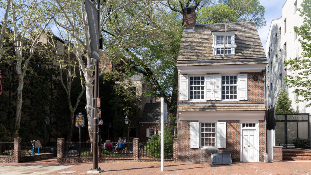Historic brick building with white window shutters in a brick courtyard.