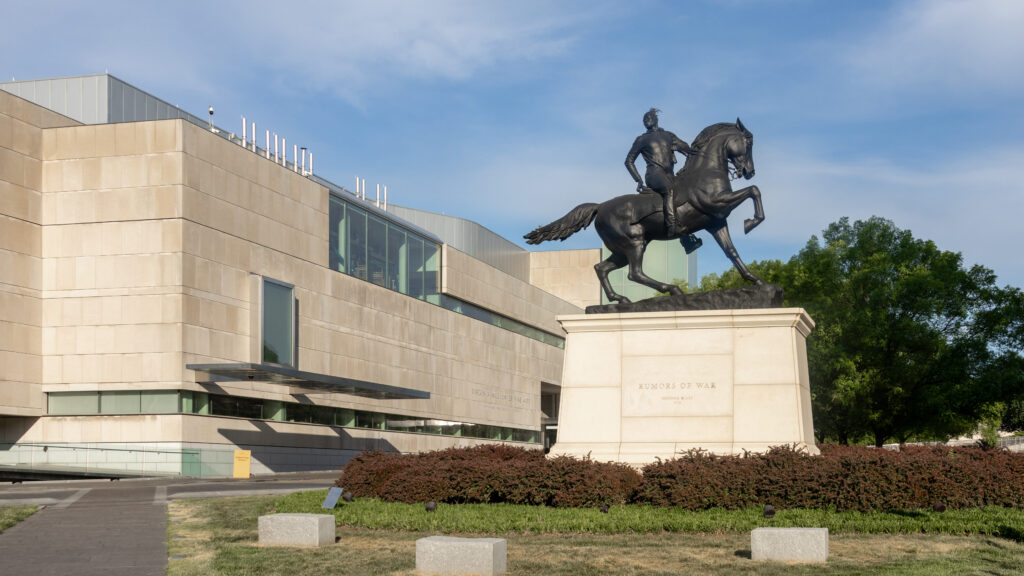 Bronze equestrian statue of a man on a galloping horse mounted on a stone pedestal.