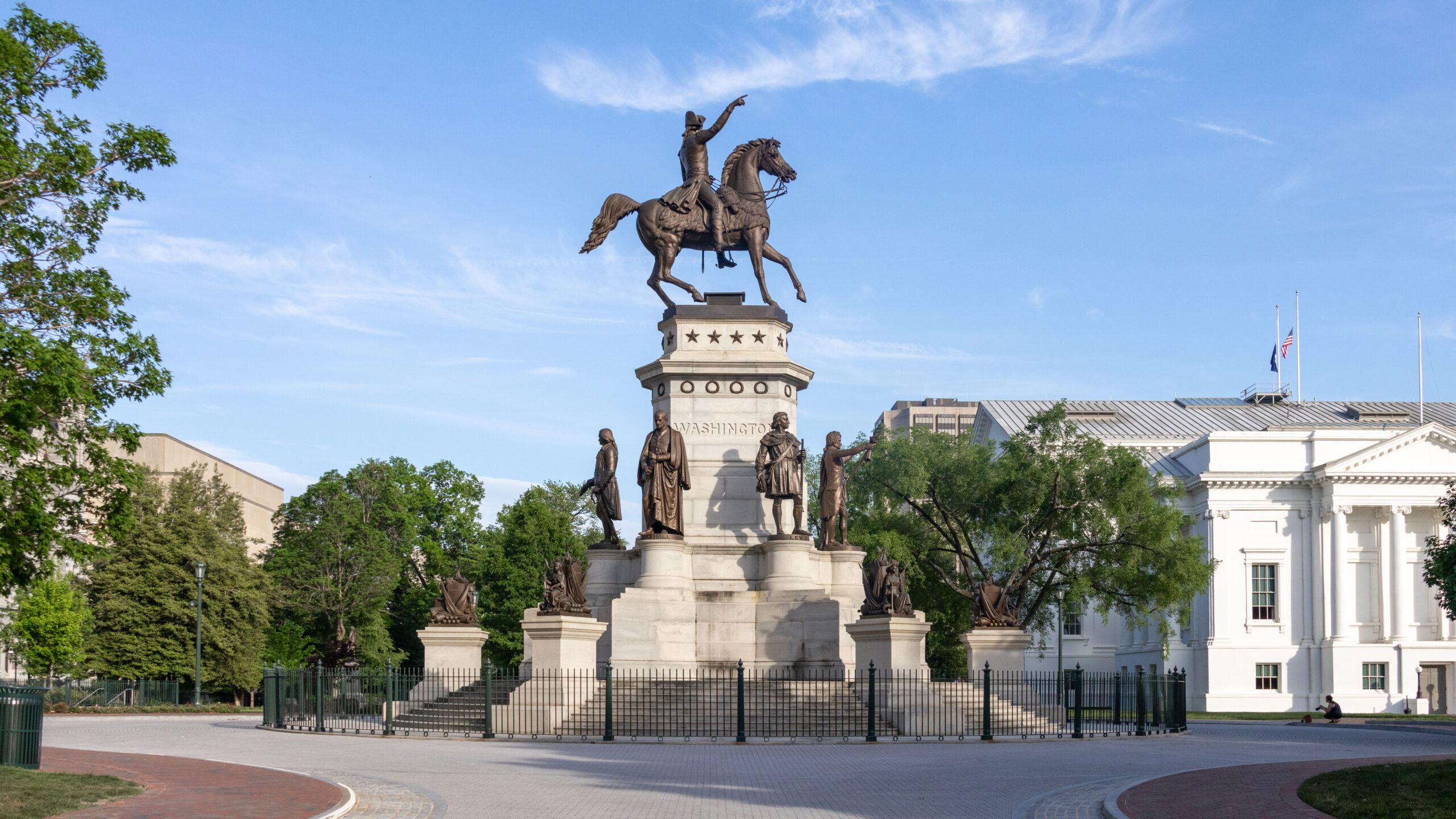 Statue of George Washington on a horse next to government building.