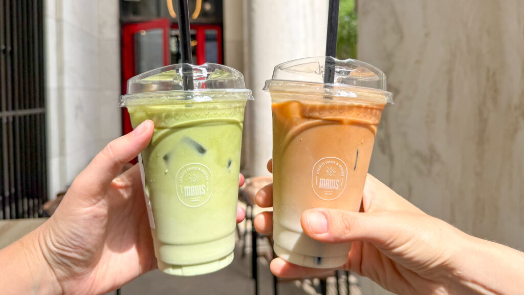 Two iced beverages raised for a toast in front of coffee shop in Philly.