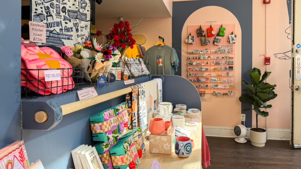 Colorful boutique counter with handmade towels, mugs, and souvenirs.