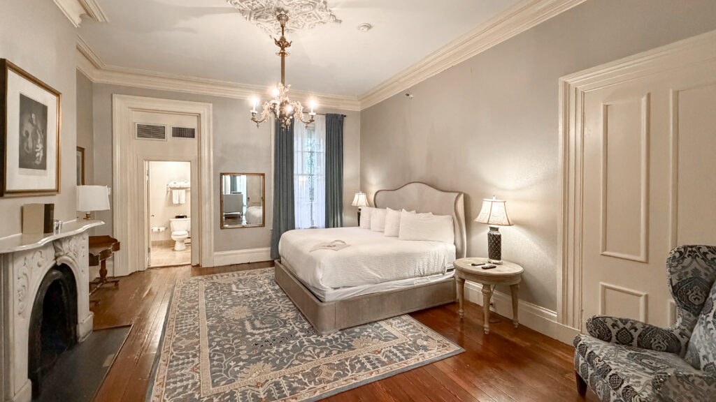 Luxurious hotel bedroom with king bed, chandelier, fireplace, and blue curtains.