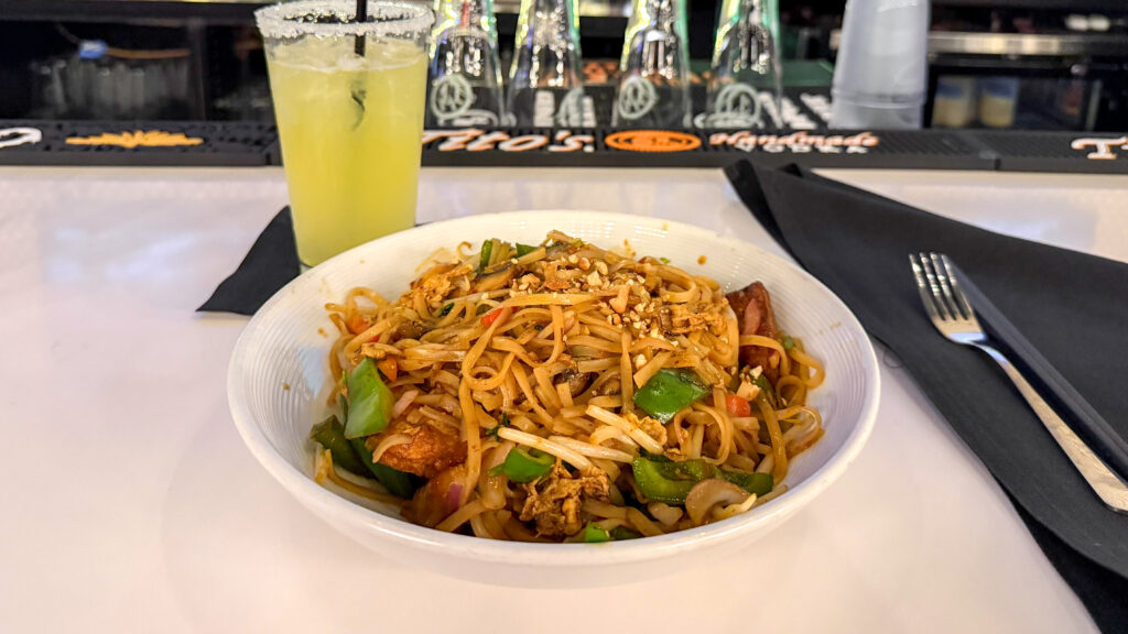 Bowl of stir-fried noodles with vegetables and tofu.