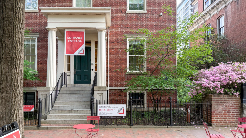 Brick townhouse entrance with white columns, green front door, and a red'Entrance' banner.