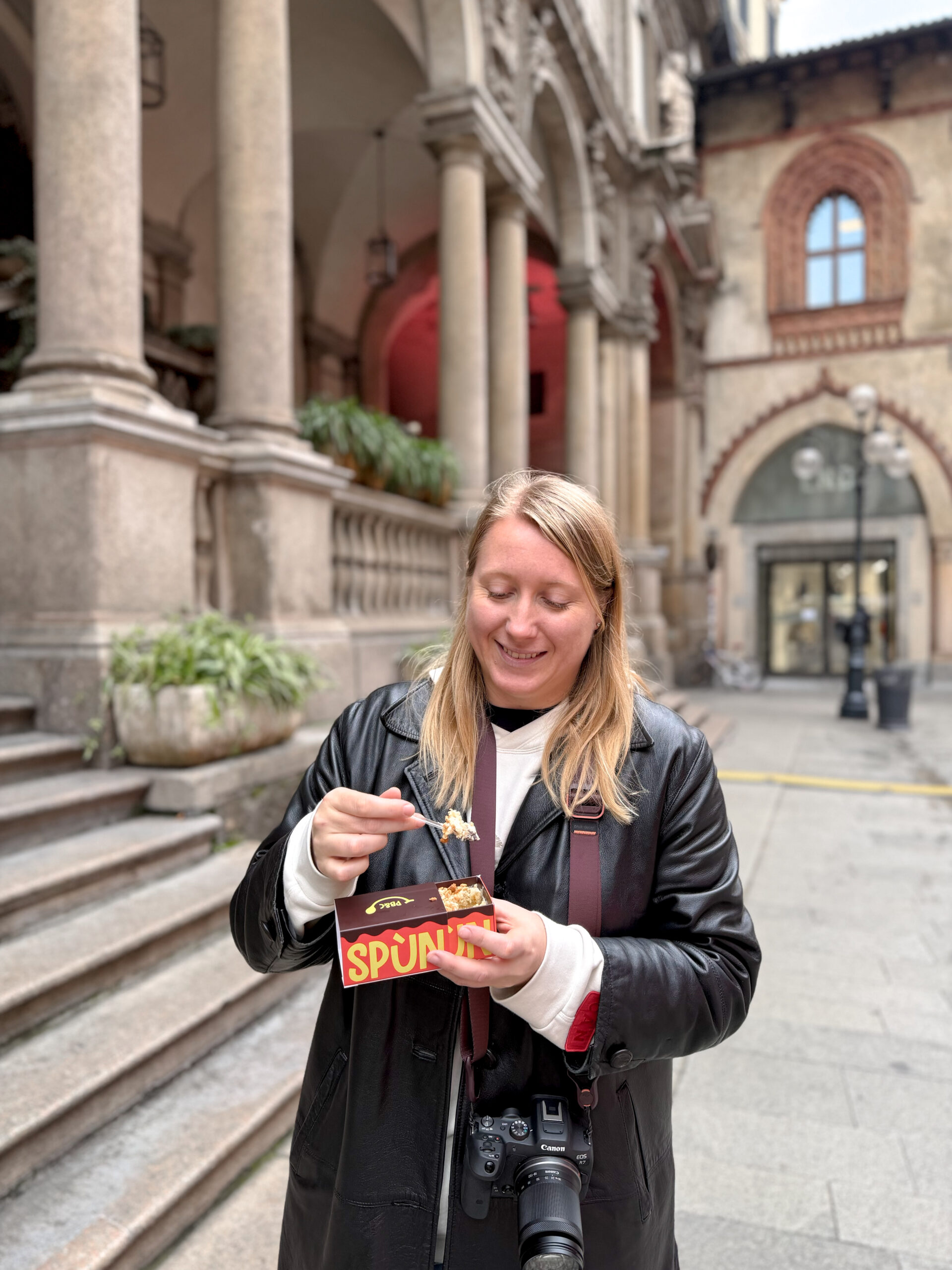 Young woman in Milan eating a tiramisu from a box.