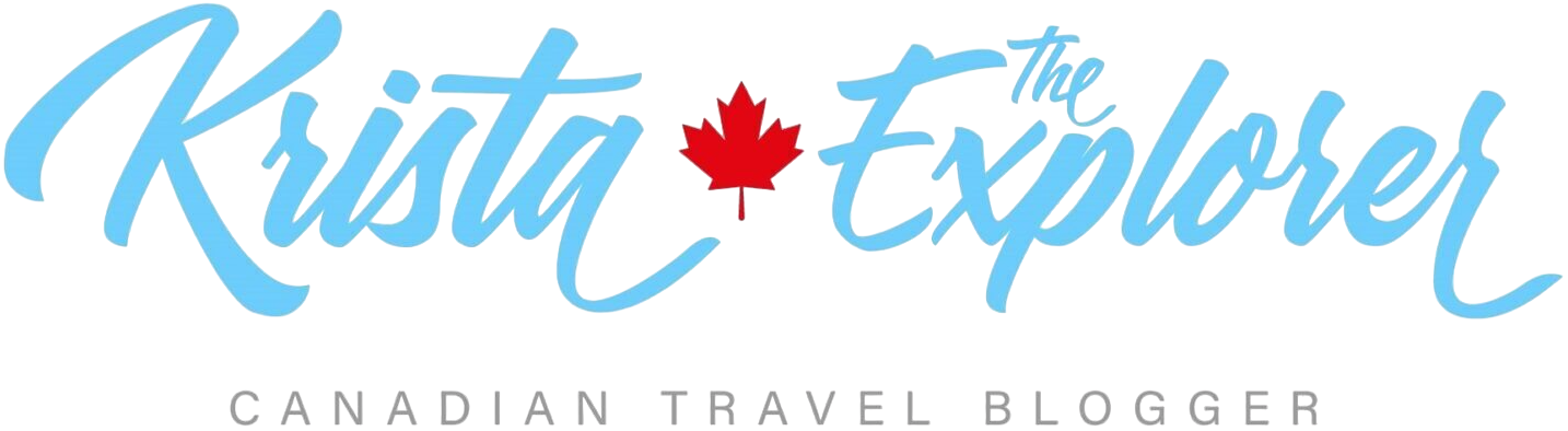 Logo for Krista The Explorer showing blue script text with a red maple leaf between words and 'Canadian Travel Blogger' beneath.