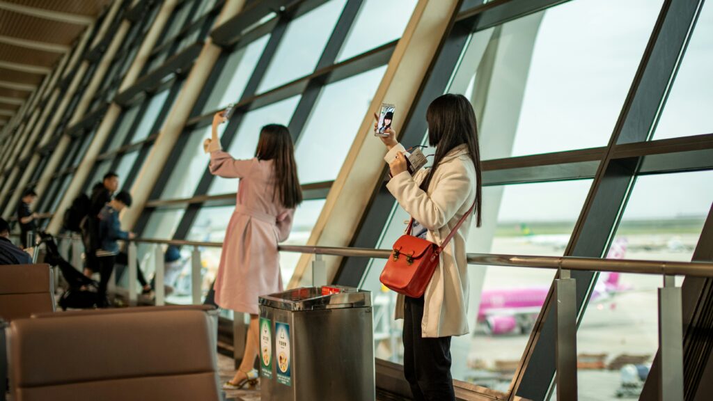 Phone Security | Krista the Explorer Two women in airport taking selfies with luggage.