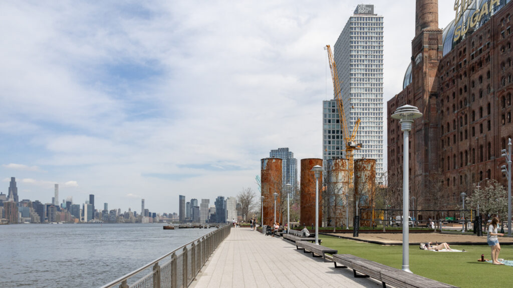 Domino Park Brooklyn | Krista the Explorer Riverside promenade beside a red brick industrial building with a yellow construction crane.