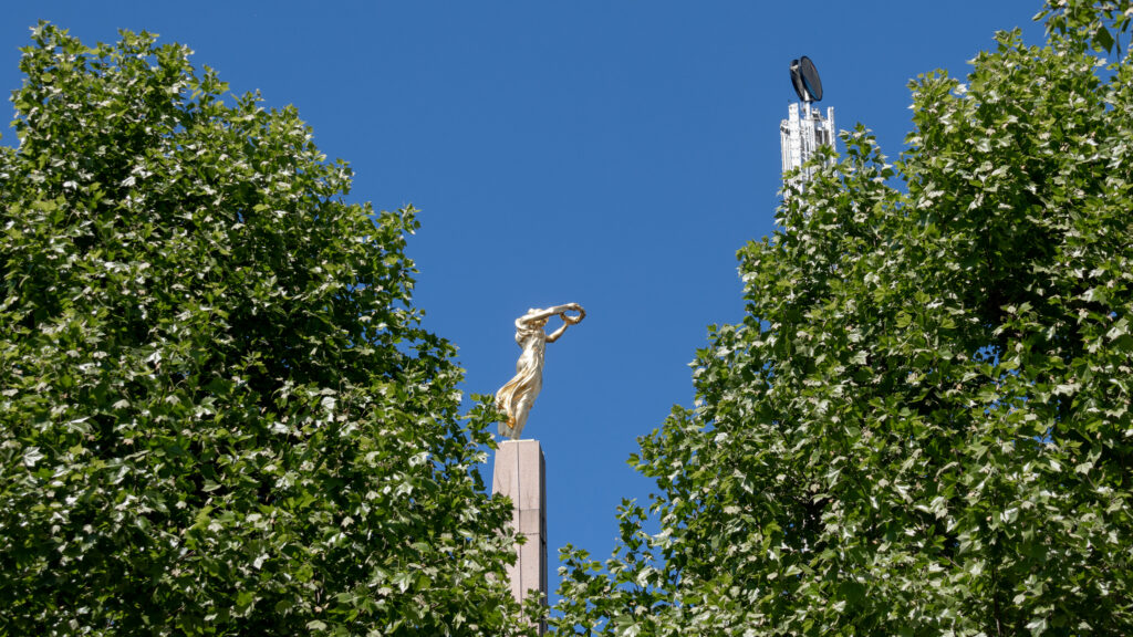 Golden Lady Luxembourg | Krista the Explorer Gold statue of a woman reaching upward atop a pedestal.