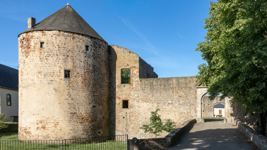 Stone fortress ruin with a rounded tower under a clear blue sky.