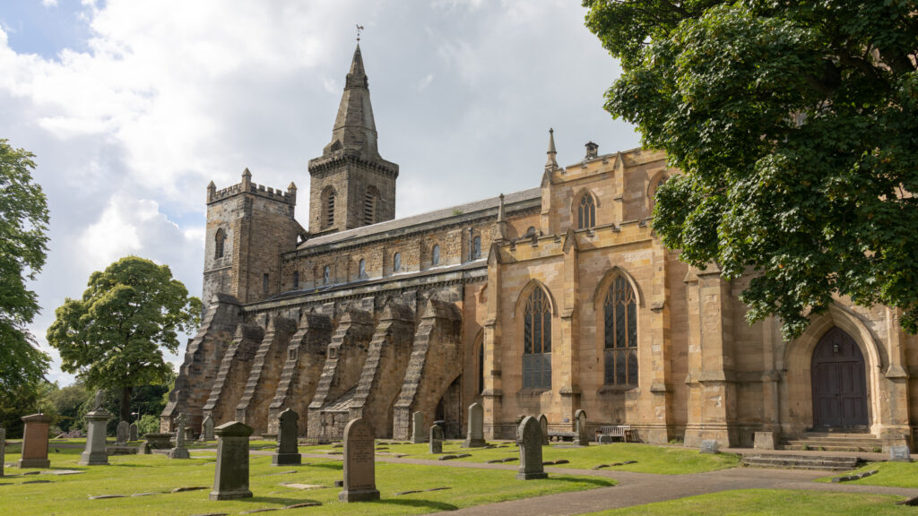Stone church with a tall spire and surrounding graveyard.