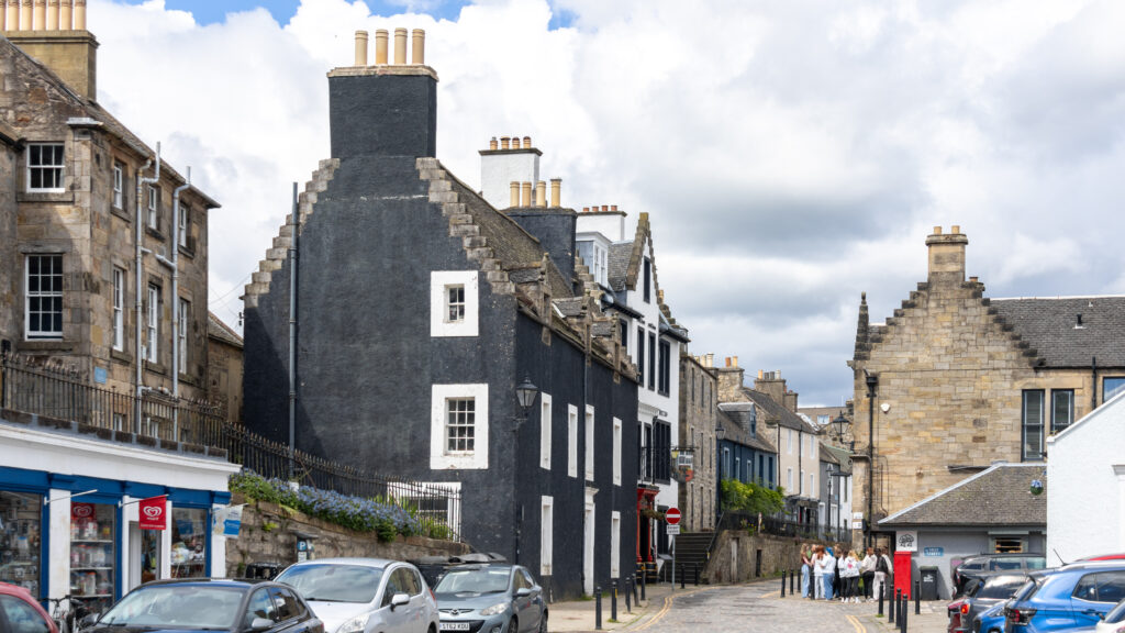 Row of historic stone houses on shopping street in Scotland.
