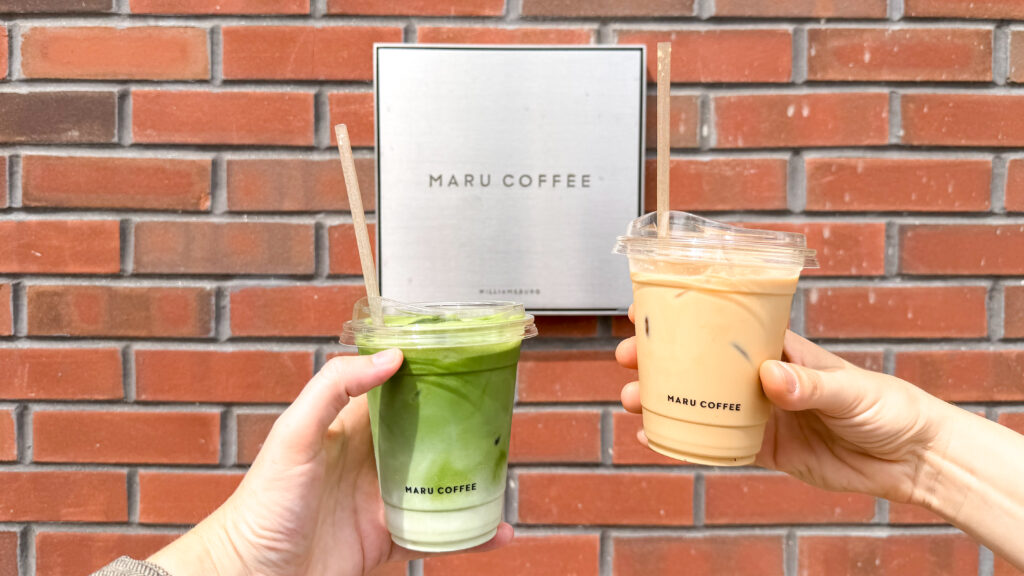 Coffee Brooklyn | Krista the Explorer Two hands hold green matcha latte and iced coffee in clear cups with straws.