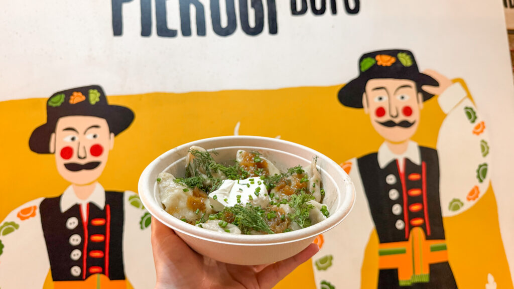 Dekalb Market Hall Brooklyn | Krista the Explorer A hand holding a bowl of dumplings topped with dill and chives.