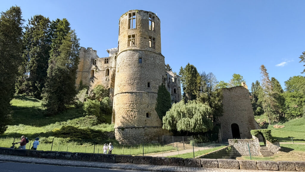 Round stone castle tower and surrounding ruin set next to rod.