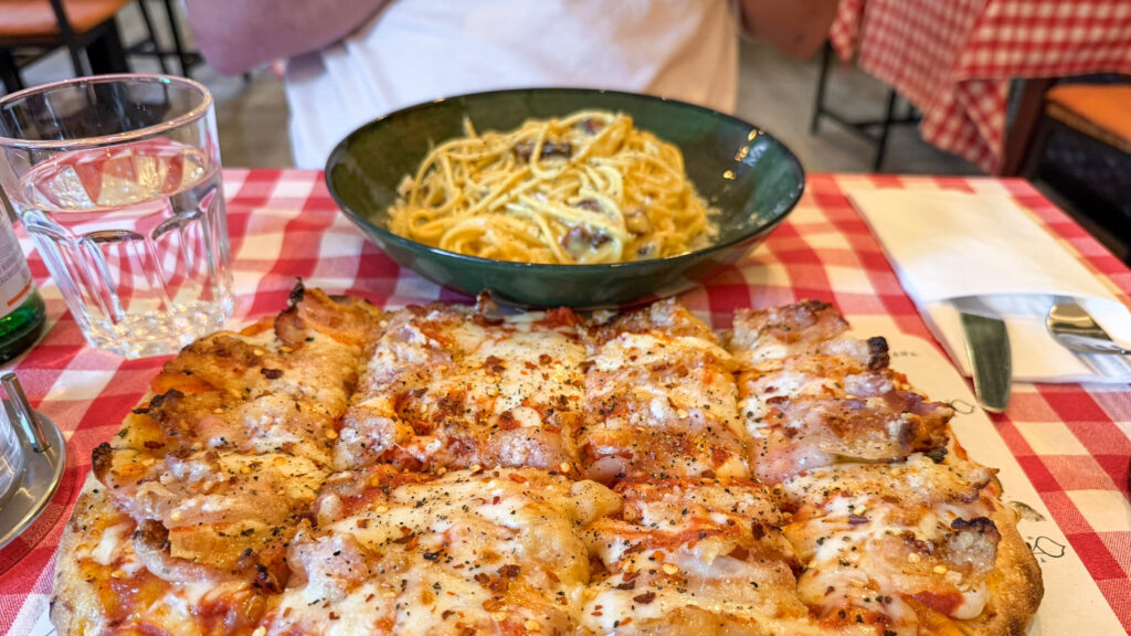 Pizza topped with melted cheese and herbs on a red-and-white checkered tablecloth.