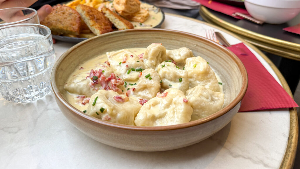 Bistro de la Presse Luxembourg | Krista the Explorer Creamy gnocchi with bacon bits and chives in a brown bowl.