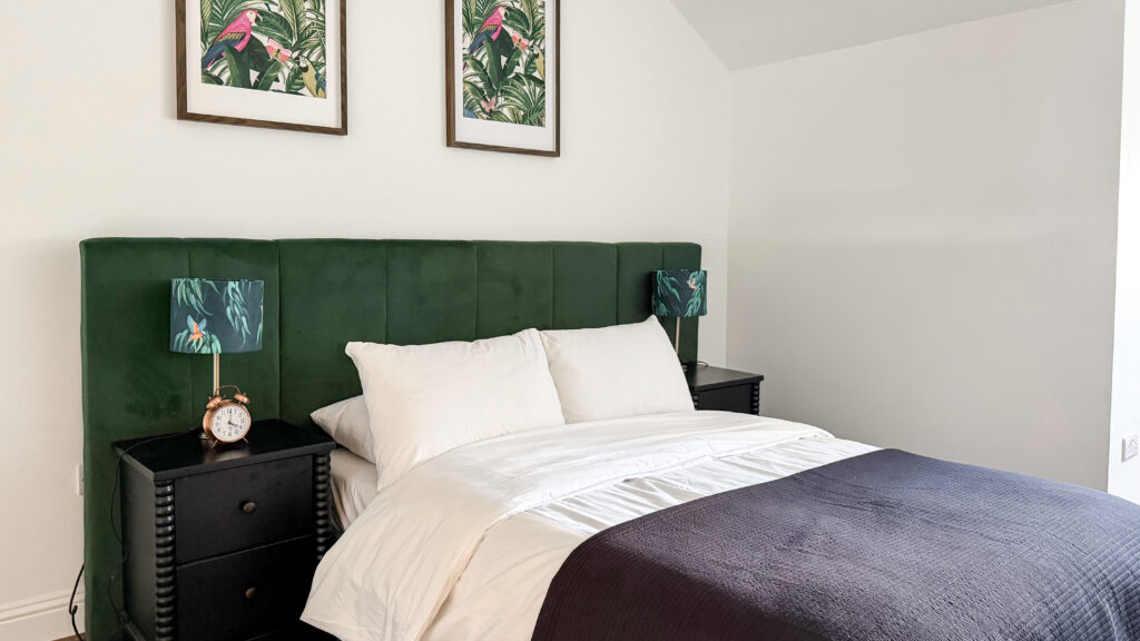 Barnet House Dunfermline | Krista the Explorer Bedroom with a dark green upholstered headboard, white bedding, and matching botanical lamps.