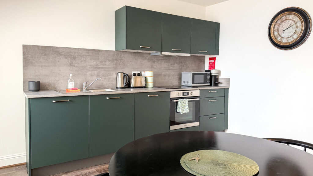 Barnet House Dunfermline | Krista the Explorer Modern kitchen with dark green cabinets, gray backsplash, and countertop appliances.