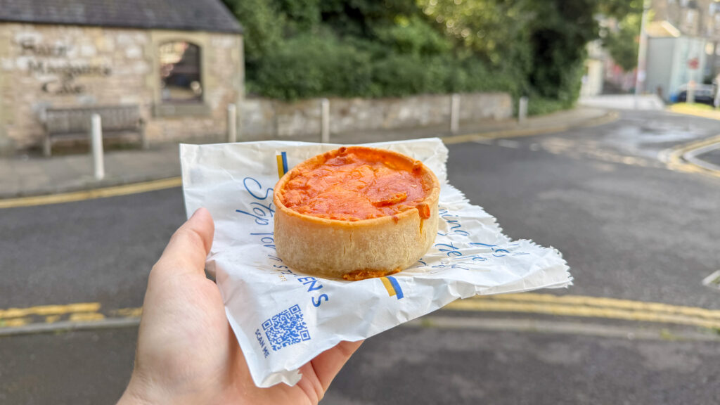 Stephen's Bakery Dunfermline | Krista the Explorer Hand holding a macaroni pie on street.