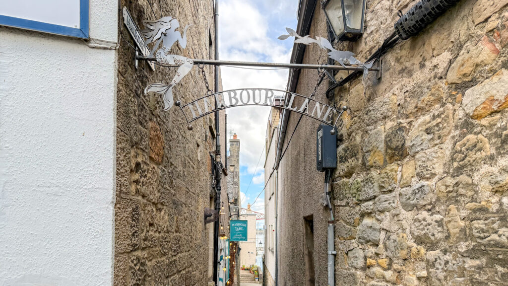 Narrow stone alley with metal sign for its name.