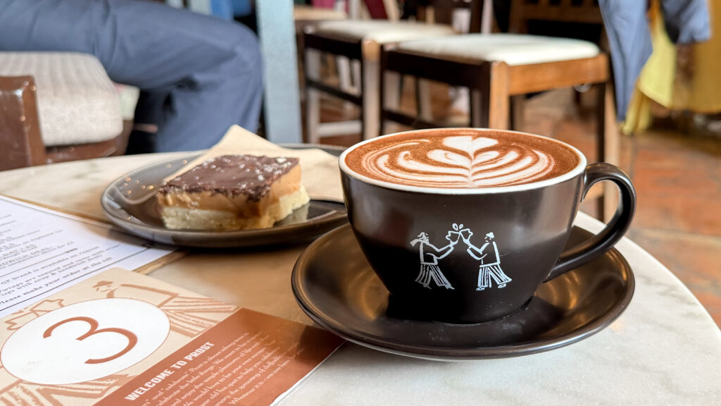 Prost Coffee Dunfermline | Krista the Explorer Black mug with milk‑foam art on hot chocolate.