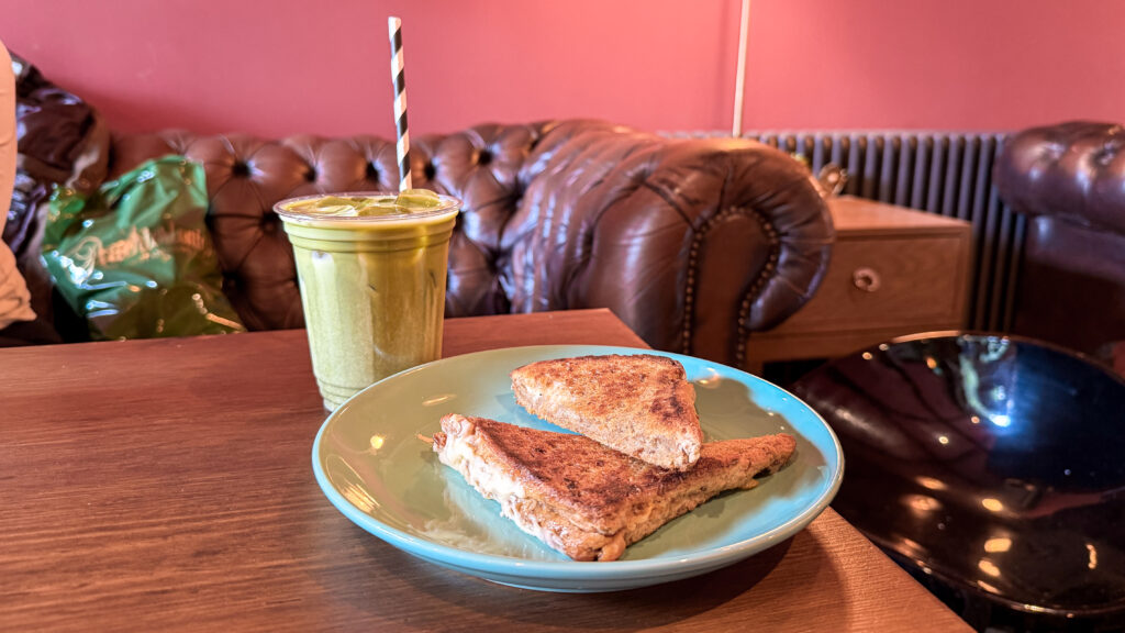 Iced matcha latte with cheese toastie on wooden table.
