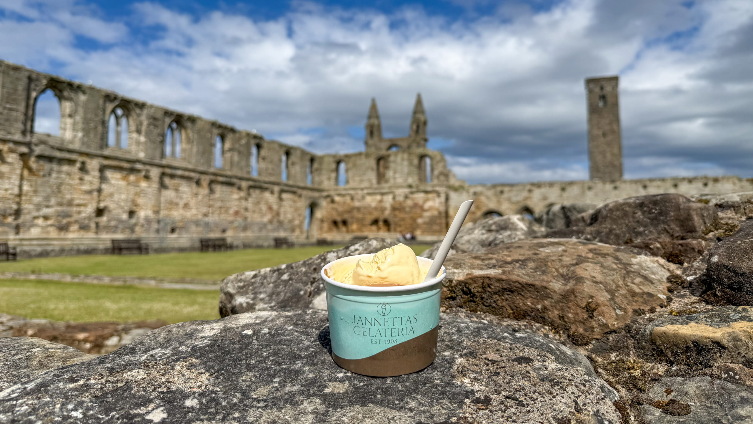 Ice cream cup labeled Jannetta's Gelateria on a rock, with medieval stone ruins in the background.