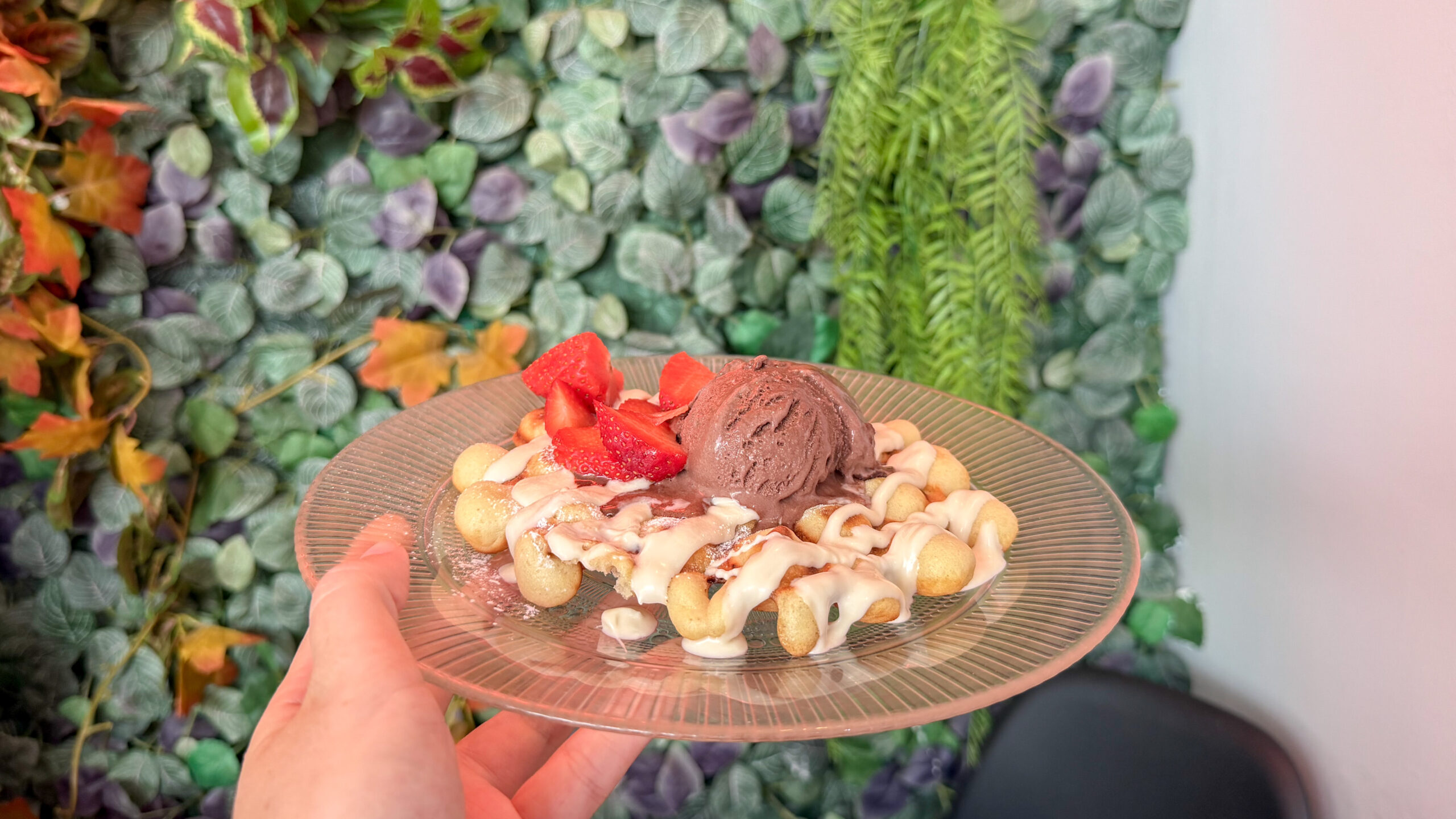Plate with bubble waffle topped with chocolate ice cream and strawberries.