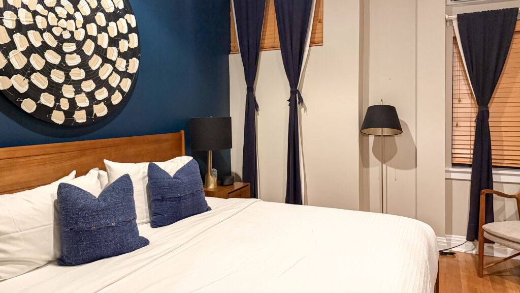 The Box House Hotel Brooklyn | Krista the Explorer Hotel bedroom with white bedding, navy pillows, and wood headboard.