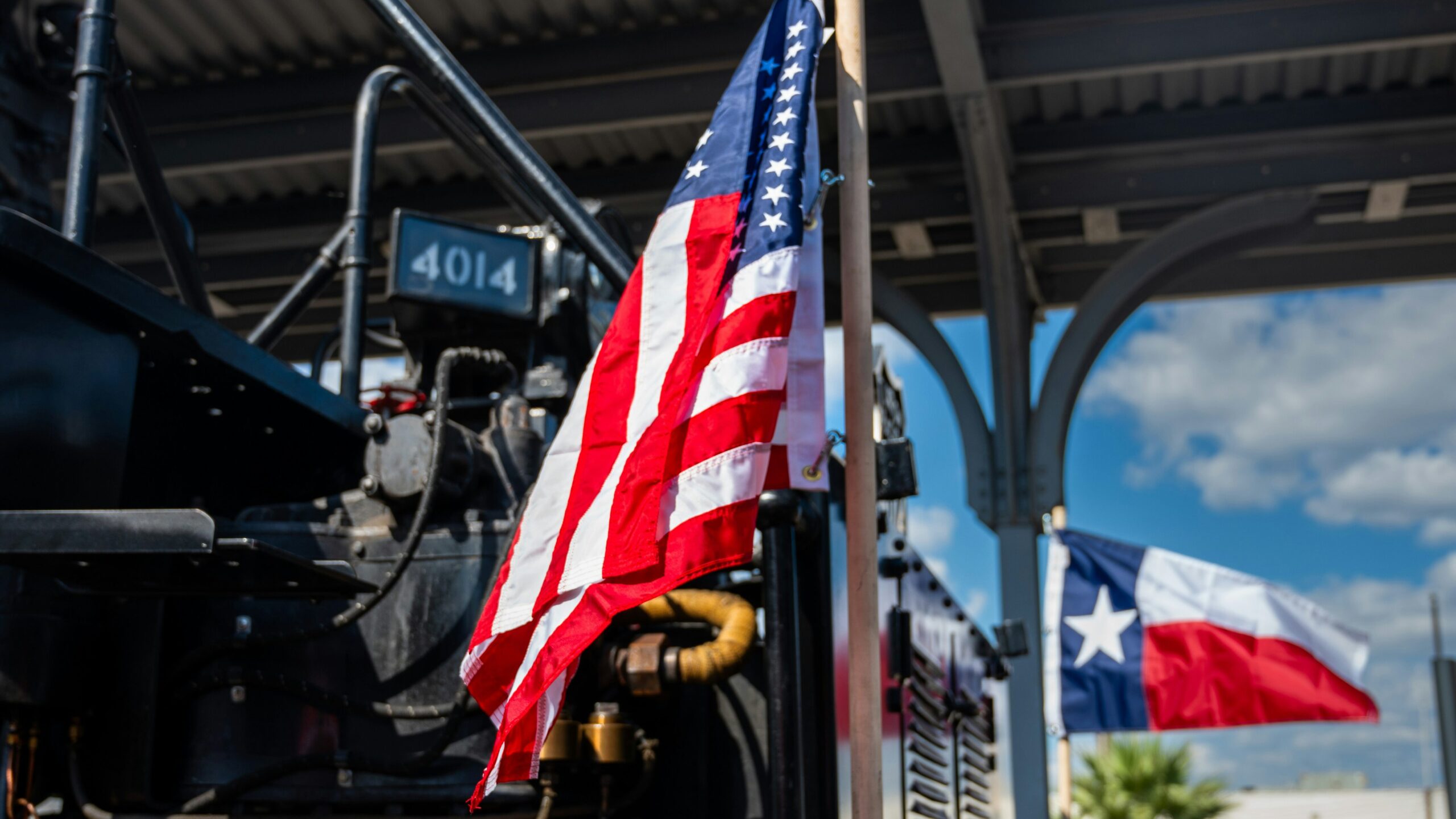 American flag draped on a steam locomotive at a rail yard.