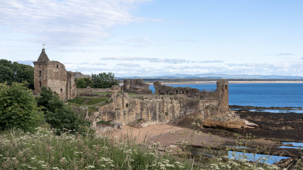 Ruins of medieval castle along coast with beach below.