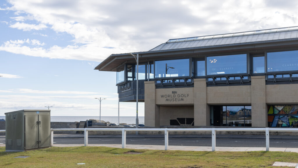 Exterior view of the R&A World Golf Museum by the sea, with a glass facade.