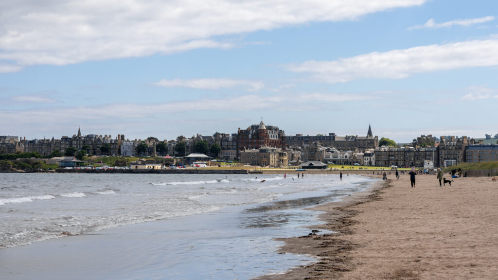 Coastal town along a sandy beach with a row of historic stone buildings.