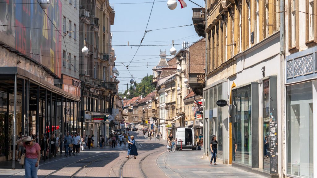Busy pedestrian shopping street with tram tracks running down the center.