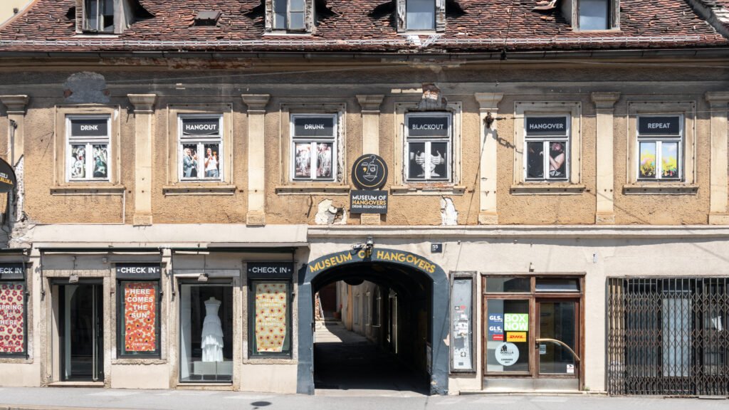 Facade of a worn beige building advertising museum in Zagreb.