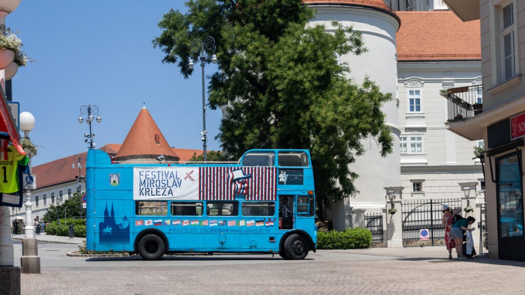 Bus Zagreb | Krista the Explorer Blue double-decker bus parked in front of cathedral.