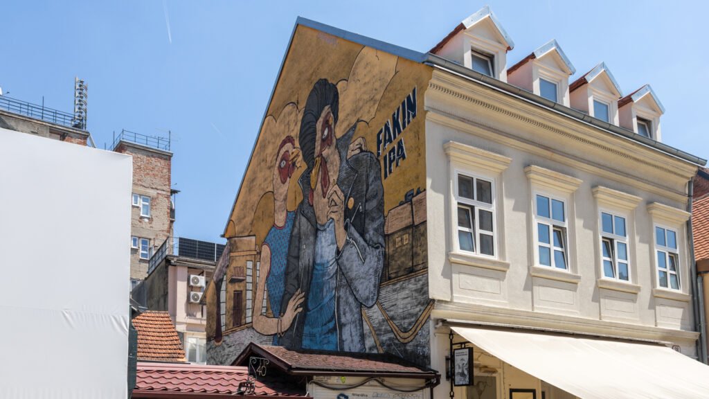 Street Art Zagreb | Krista the Explorer Facade of a building with a large colorful mural depicting cartoon people.