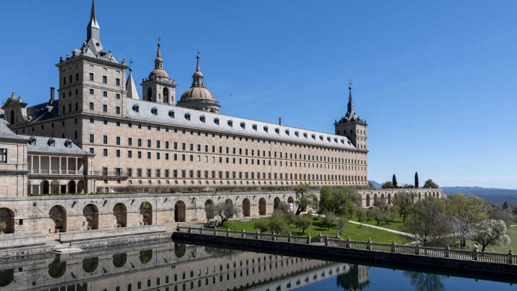 View of monastery next to small lake and gardens.