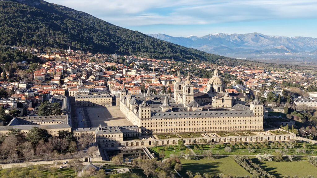 Aerial view of historic monastery with mountains in the background.
