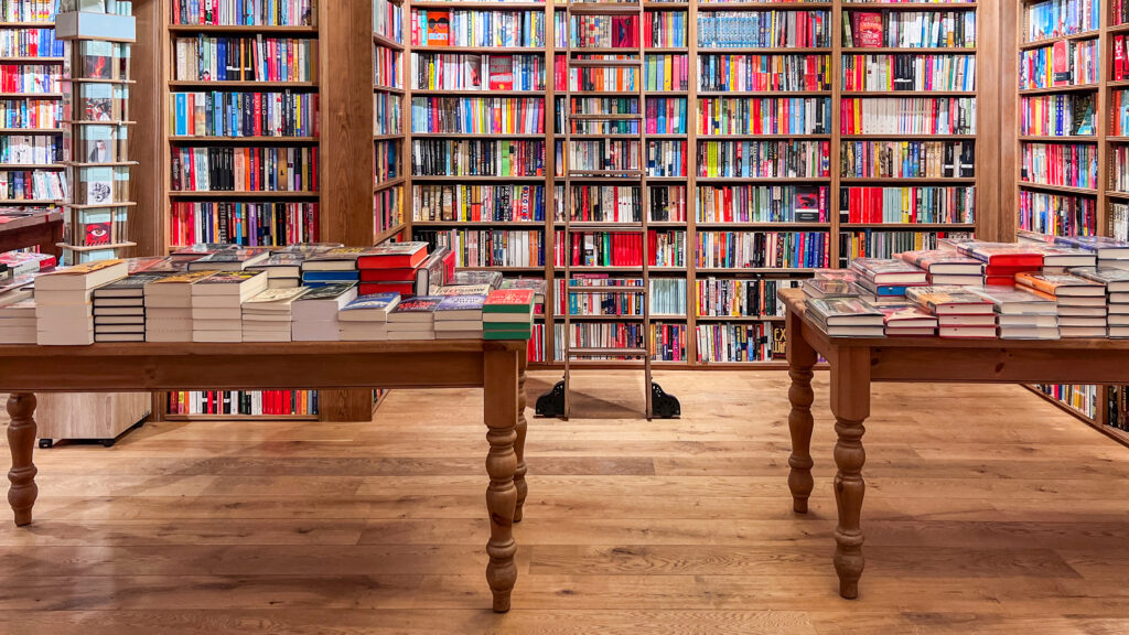 Interior of a bookstore with wooden shelves and tables.
