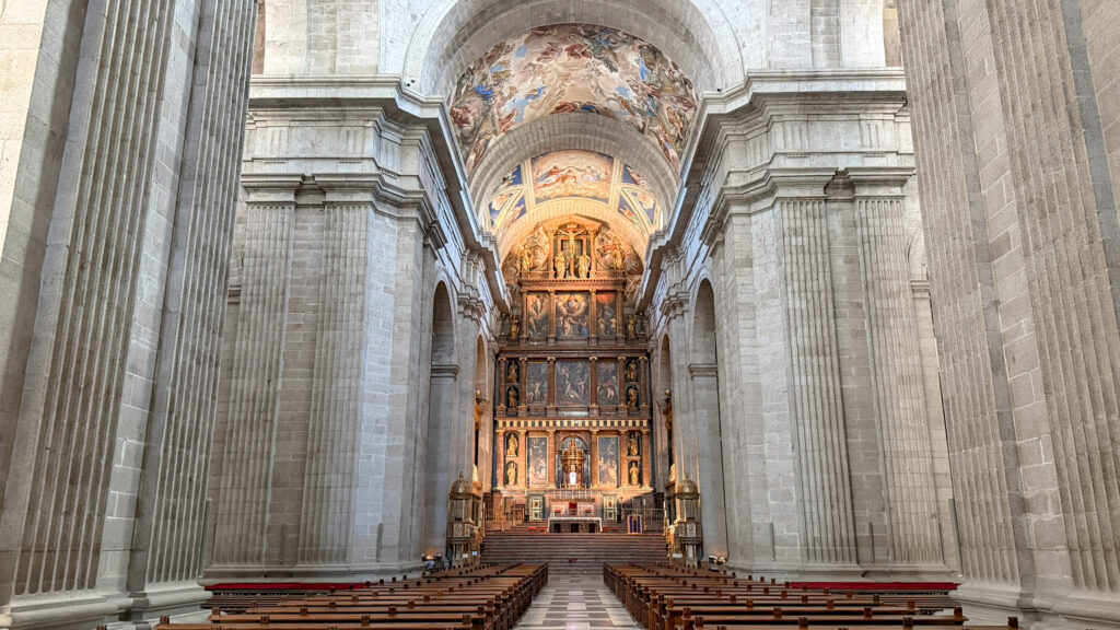 Stone cathedral interior with tall columns, arches, and ornate altar.